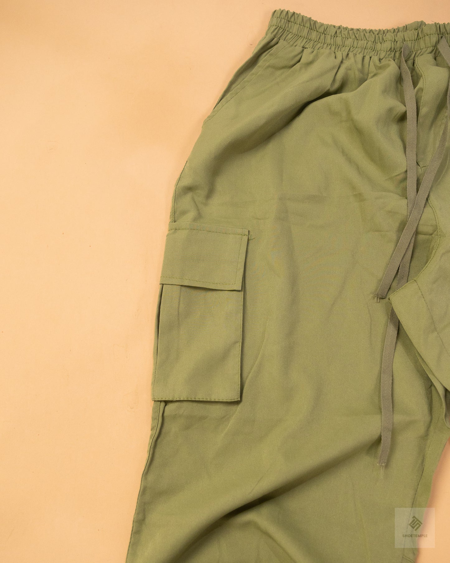 khaki green cargo pants featuring side pockets, a drawstring waist, and adjustable ankle ties