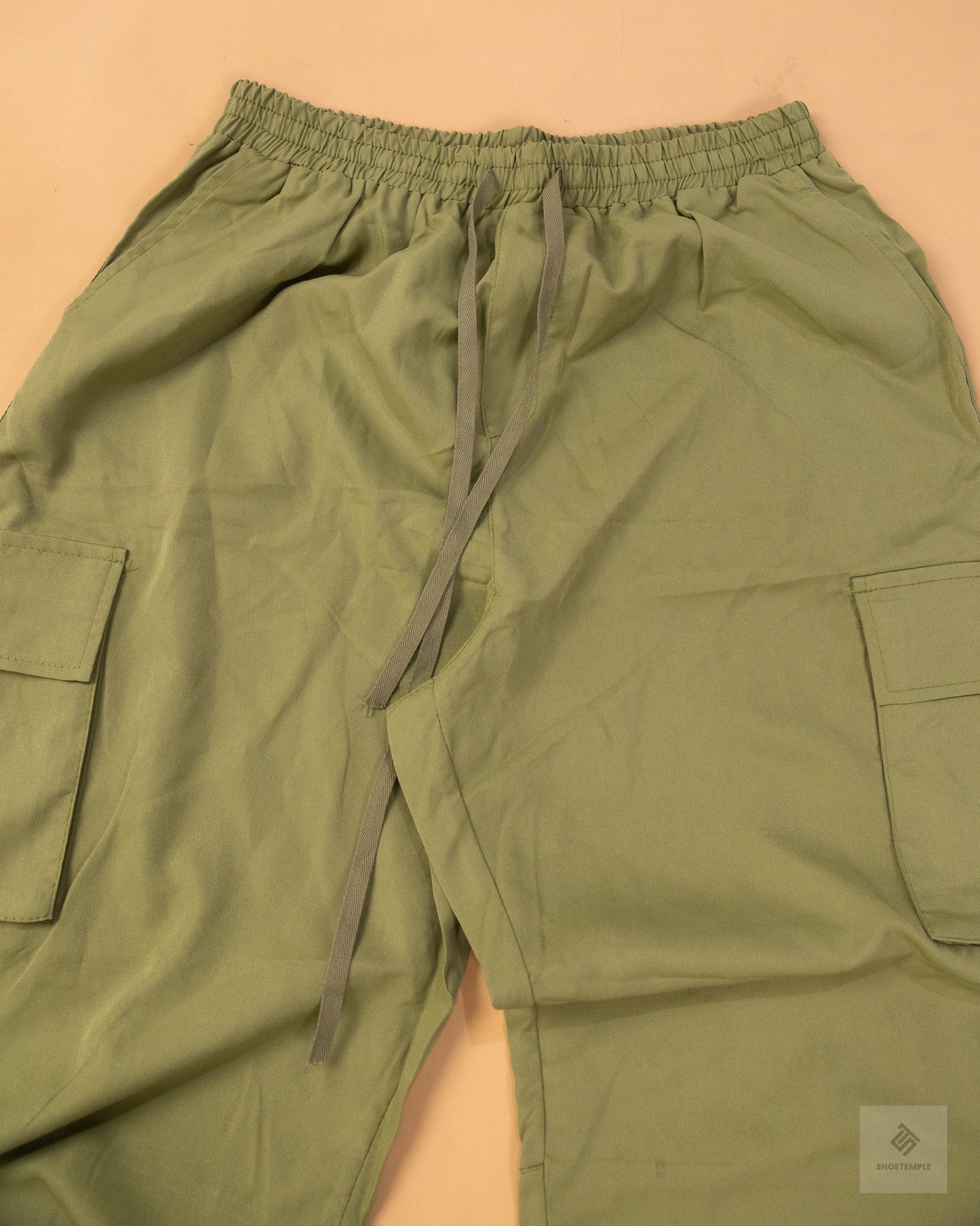 khaki green cargo pants featuring side pockets, a drawstring waist, and adjustable ankle ties